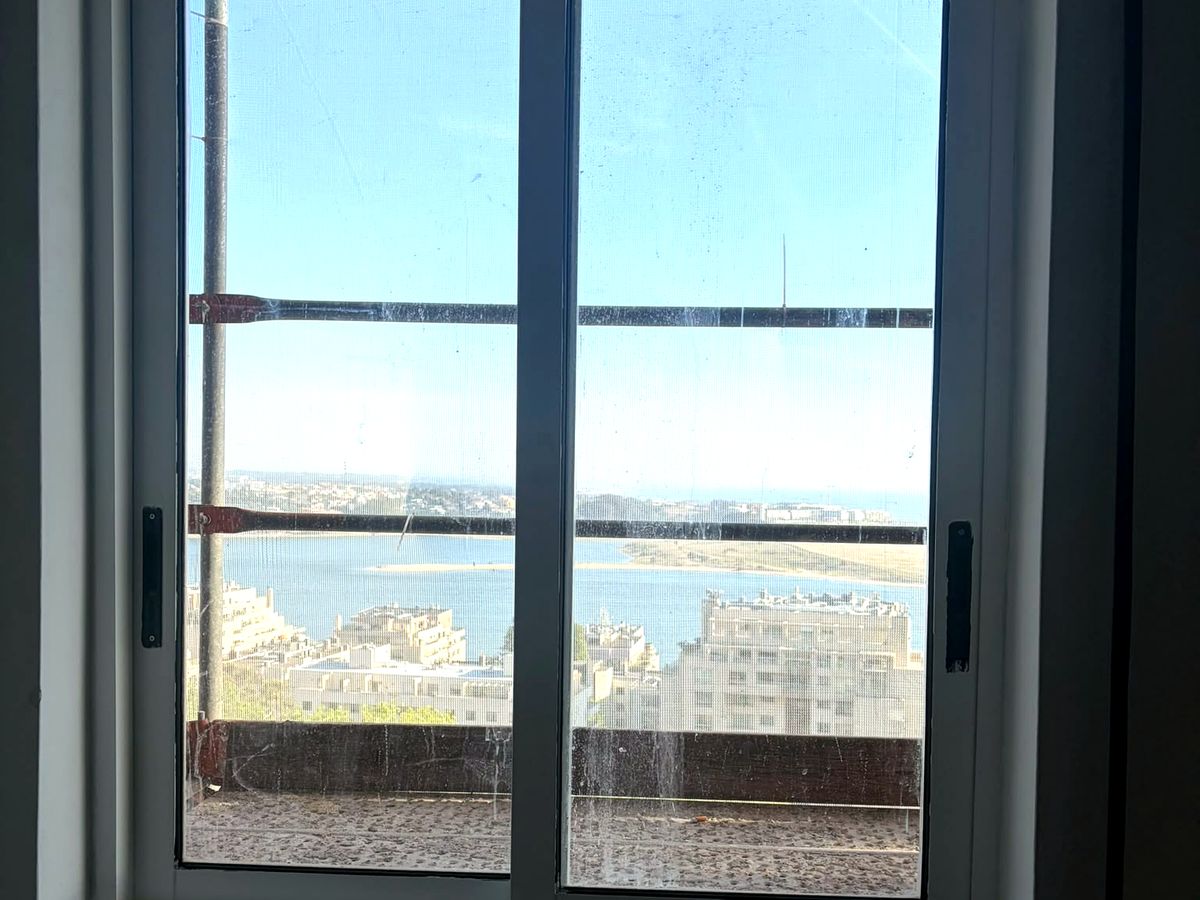 Caixilharia de madeira pintada de branco pela Dizarro, com vista de mar