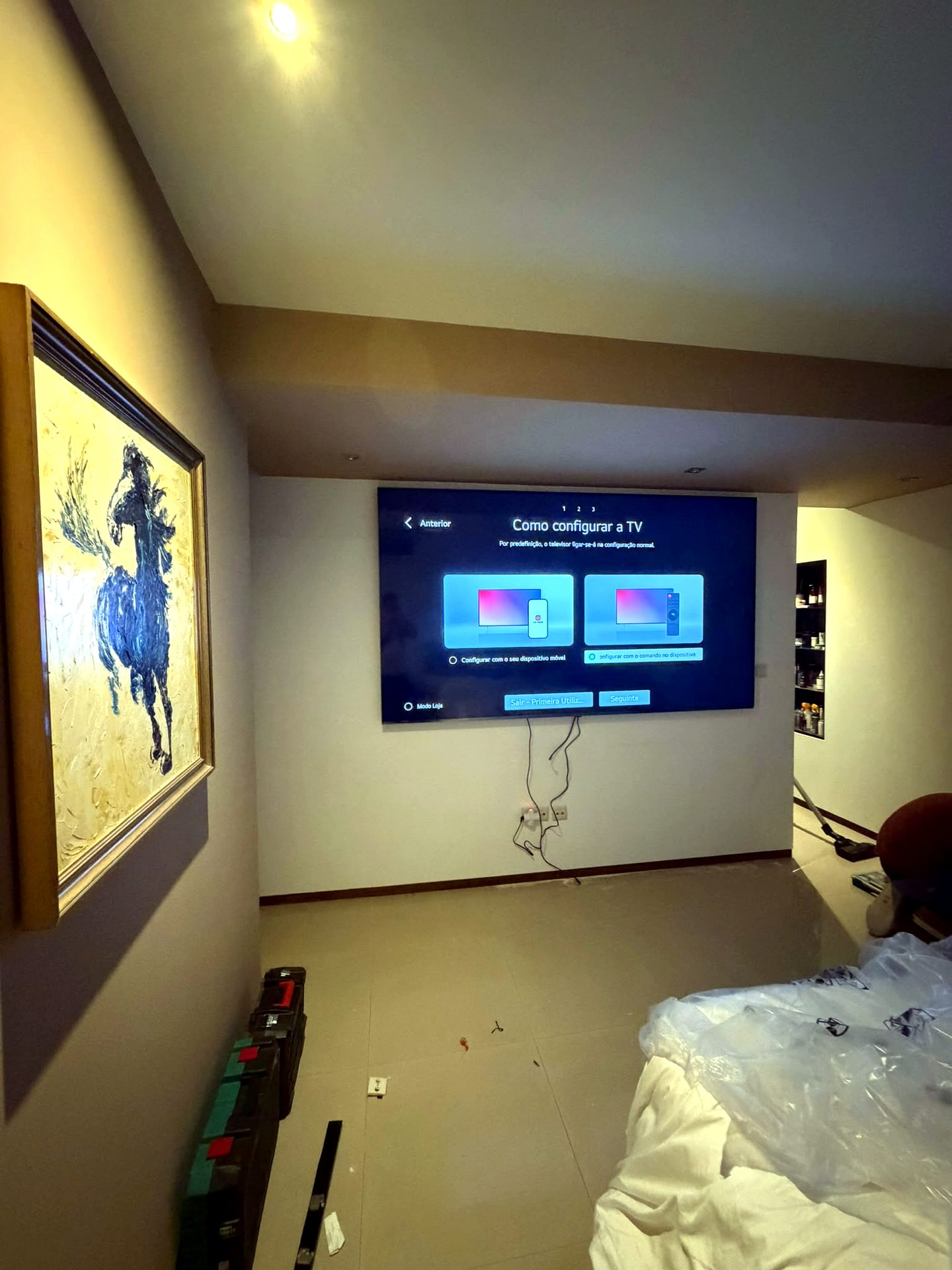 Televisor a ser configurado numa sala, com proteção de obra no chão